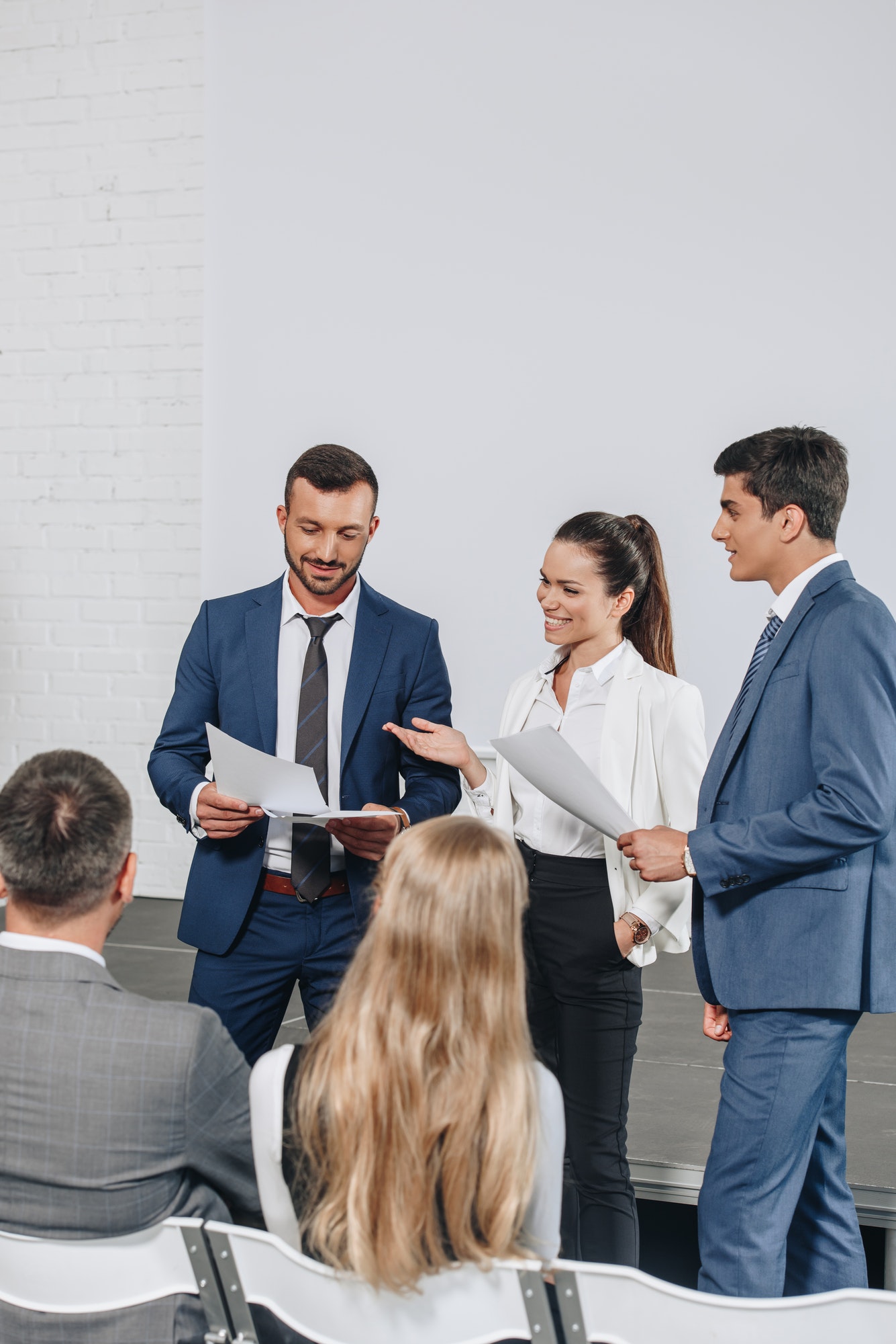 smiling businesspeople talking about documents during training in hub